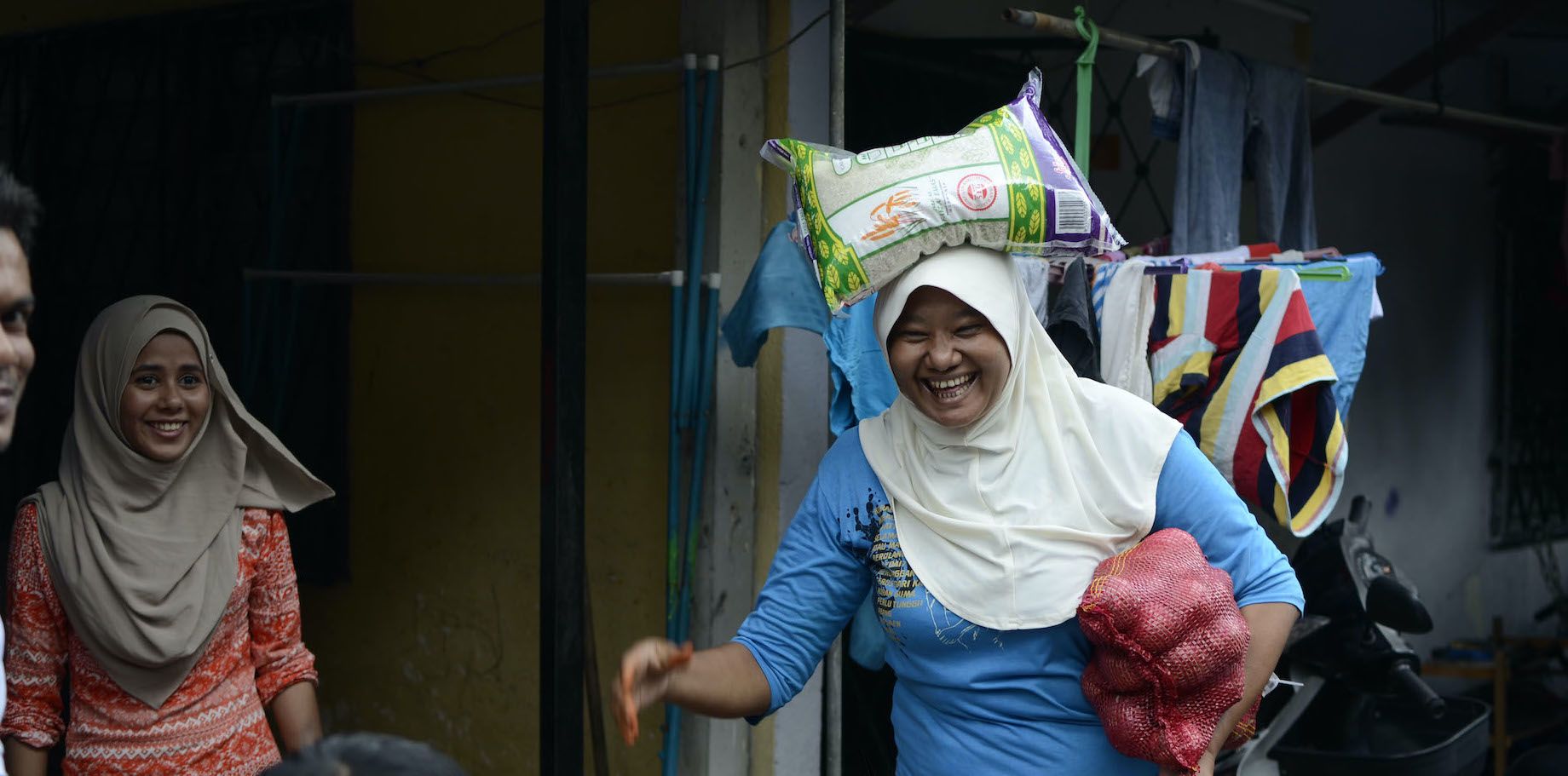 A woman carries a heavy bag of rice on her head, which are among the groceries distributed by social enterprise Reyna Movement for refugee households in need.