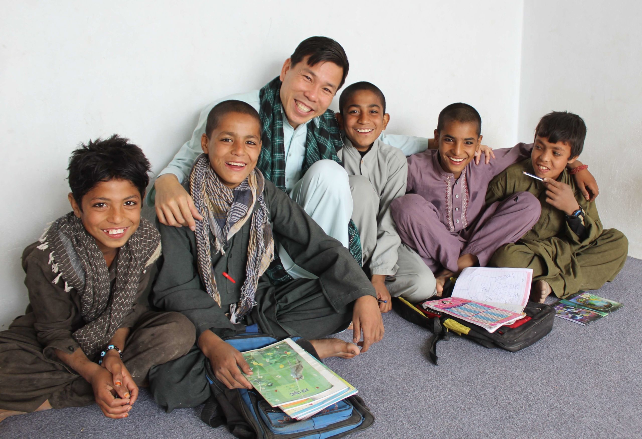 Dr Hakim sits with a group of five Afghan boys on the floor of a classroom at a camp for internally displaced persons in Afghanistan.