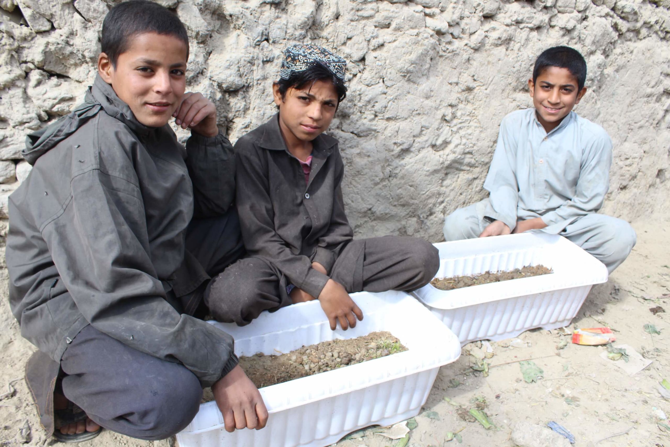 Two youth show off their permaculture planter boxes, as part of a workshop by NGO Afghan Peace Volunteers to help Afghan youth displaced by conflict to learn skills.