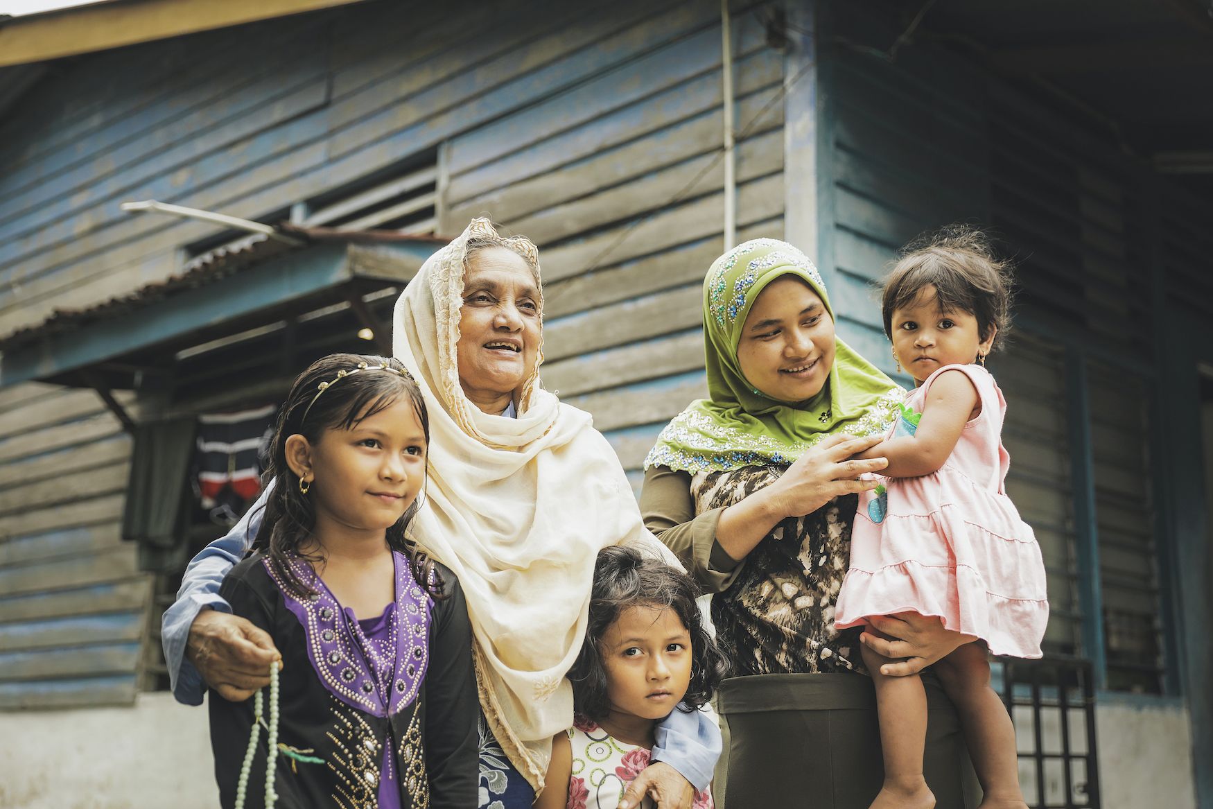 Two Rohingya women refugees and their children gather before their home in Malaysia, where they await resettlement after fleeing their homes. 
