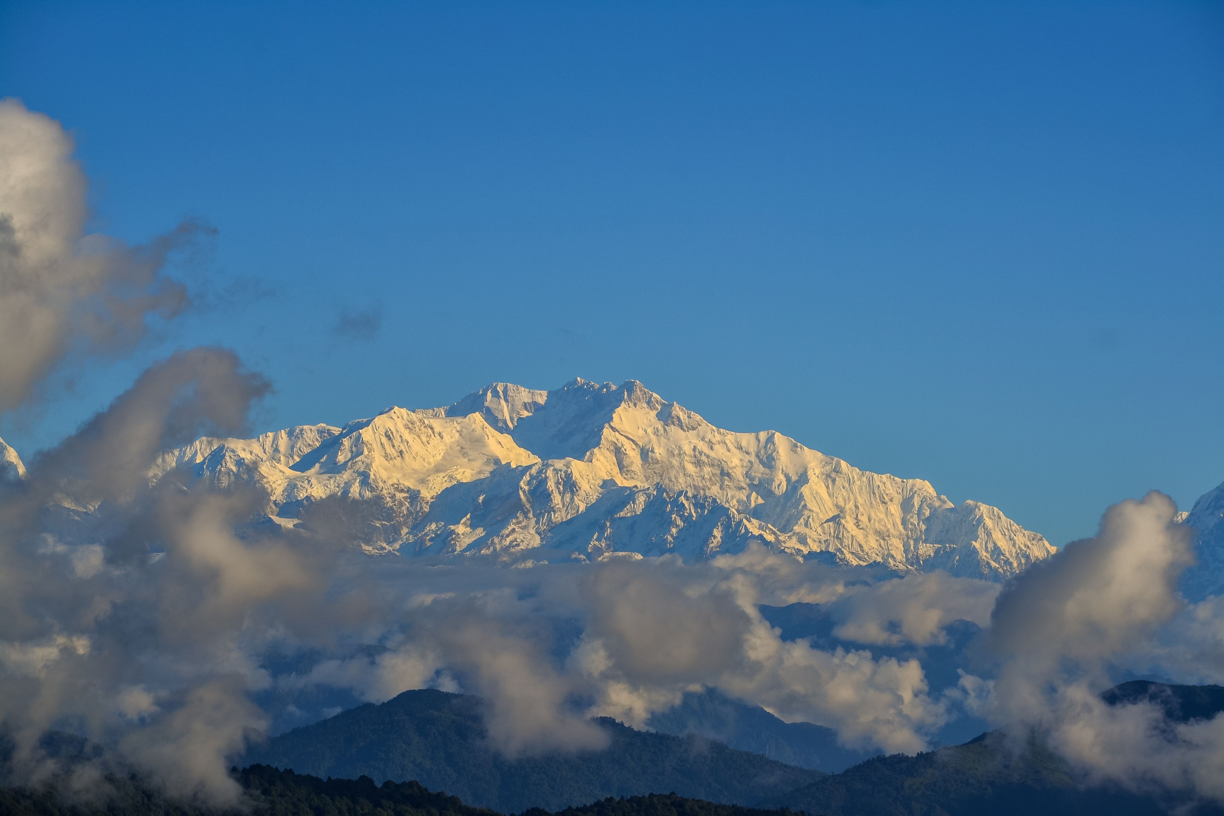 A sunlit patio of simple house in the Himalayas overlook steep green mountains in the background